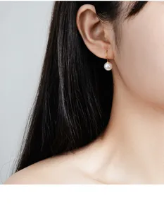 Detailansicht eines eleganten Sterlingsilber Perlenohrrings am Ohr nah fotografiert.