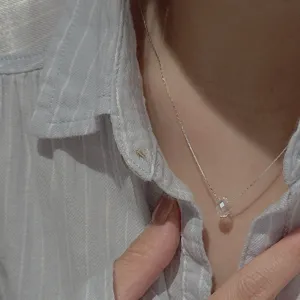 Detailed close-up of a minimalist silver clavicle chain featuring a clear faceted crystal pendant.