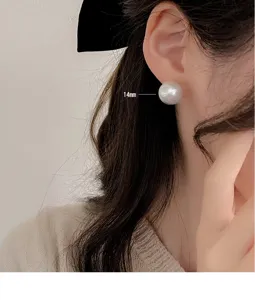 Nahaufnahme eines großen 14 mm weißen Perlenohrrings, der elegant am Ohr getragen wird.