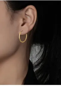 Nahaufnahme eines minimalistischen goldenen Creolen Ohrrings, elegant am Ohrläppchen.