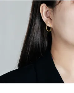 Detailaufnahme von einfachen goldenen Creolen am Ohr, minimalistischer Alltagsschmuck.