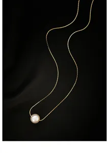 Nahaufnahme Detailansicht einer filigranen goldenen Silberkette mit einer runden Perle.