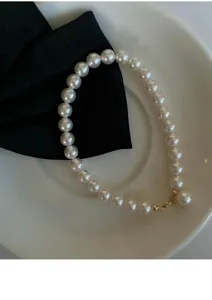 Nahaufnahme Detail des eleganten Perlenarmbands mit glänzenden weißen Perlen und Verschluss.