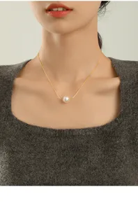 Nahaufnahme einer eleganten Einzelperlen-Anhänger-Halskette an einer feinen Goldkette am Modell.