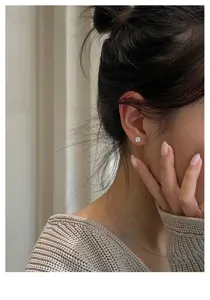 Nahaufnahme eines minimalistischen Zirkon Ohrsteckers am Ohr, Silber, Detailansicht.