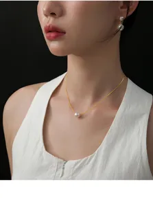 Nahaufnahme einer eleganten Einzelperlen-Halskette mit goldener Kette am Hals des Modells.