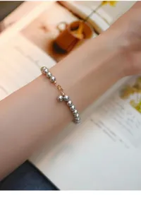 Detailansicht eines filigranen grauen Perlenarmbands mit silbernen Elementen und Anhängern.