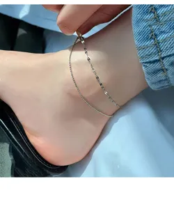 Detail shot of a delicate double layer silver anklet on ankle, showing fine bead chain links.