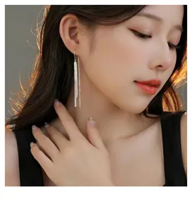 Gros plan détaillé de boucles d'oreilles longues et scintillantes en argent sterling.