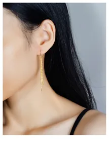 Vue rapprochée détaillée des boucles d'oreilles à pampilles doubles dorées étincelantes.