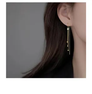 Gros plan détail de boucles d'oreilles longues pampilles étoile en argent, style pendant.