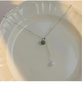 Detail shot of the adjustable double bead pendant necklace with pearl and green stone.