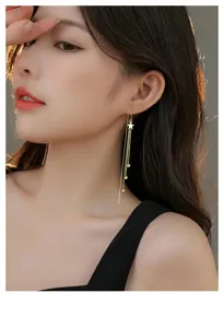 Détail exquis de boucles d'oreilles longues à franges d'étoiles, design doré chic.
