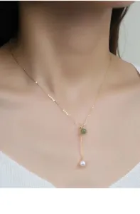 Detail view of the delicate s925 silver lariat necklace with green jade and white pearl charms.
