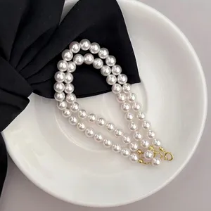Elegantes doppelreihiges weißes Perlenarmband mit goldenen Verschlüssen für stilvolle Auftritte.