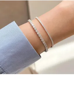 Nahaufnahme von funkelnden Zirkonia Tennisarmbändern im Doppel-Design am zarten Handgelenk.