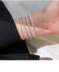 Detailaufnahme von vier glitzernden Zirkon Silber Tennisarmbändern am Handgelenk.