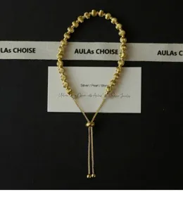 Primer plano de la pulsera deslizante de cuentas chapadas en oro con textura fina.
