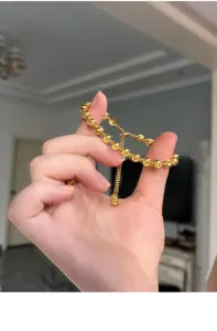 Primer plano detallado del elegante brazalete de cuentas doradas con cierre ajustable.