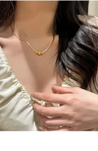 Detailopname van de elegante gouden slangenhalsketting met verfijnde kralenhangerdetails.