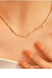 Detaillierte Nahaufnahme einer eleganten goldenen Schlangenkette, die sanft am Hals liegt.