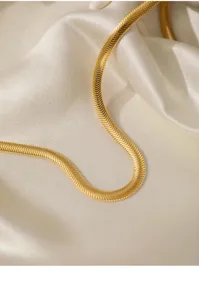 Nahaufnahme einer eleganten 4mm goldenen Schlangenkette auf feinem Seidenstoff präsentiert.