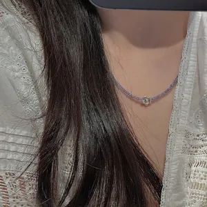 Primo piano di una collana di perle viola vintage con ciondolo a fiore in argento.
