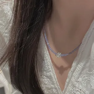 Primo piano dettagliato della collana con perline in tanzanite viola e ciondolo a fiore.