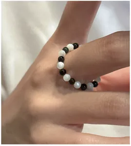 Gros plan sur la bague en perles noires et blanches pour présenter les détails du bijou fin.