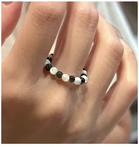 Vue détaillée d'un bague de perles vintage avec perles noires et blanches portée, design élégant.