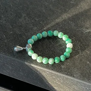 Vue détaillée d'une bague de perles vertes de style coréen avec pendentif argenté.