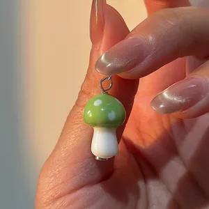 Primer plano detallado de un lindo dije colgante de seta verde y blanca con anilla plateada.