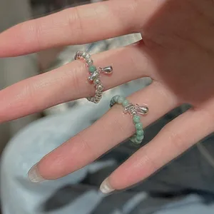 Gros plan de bagues de perles vintage avec pierres vertes et pendentifs en argent.