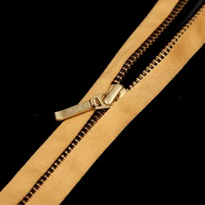 Detail shot of a golden metal zipper on black fabric garment, fine craftsmanship.