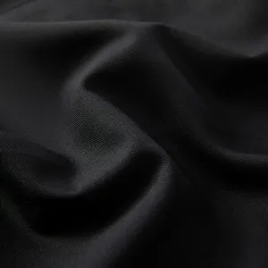Premium black suit fabric detail close-up showing fine texture and smooth drape.