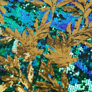 Nahaufnahme des Paillettenstoffs mit goldener Blattstickerei und buntem Hintergrund.