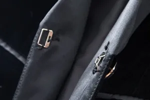 Close-up detail of women's gold velvet blazer metal hook closure, elegant texture design.