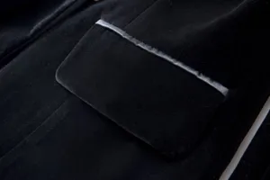 Close-up detail of black velvet blazer pocket, highlighting soft texture and refined piping.