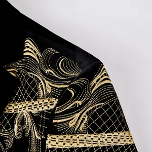 Detailed close-up of mens black velvet suit jacket with intricate gold embroidery pattern.