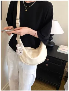 Dettaglio borsa a spalla hobo in pelle bianco crema con un grazioso ciondolo in peluche.