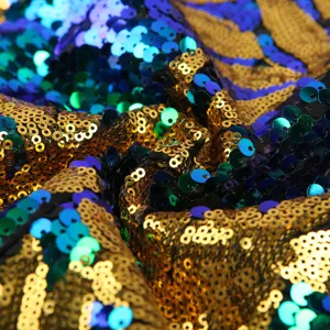 Detailaufnahme von funkelndem Paillettenstoff mit goldenem und blauem Blattmuster für Showkostüme.