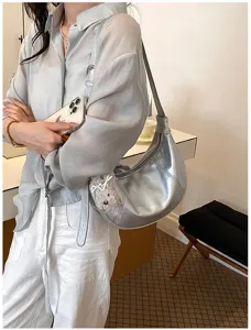 Dettaglio borsa a spalla metallica argento, elegante borsa a mezzaluna con ciondolo.
