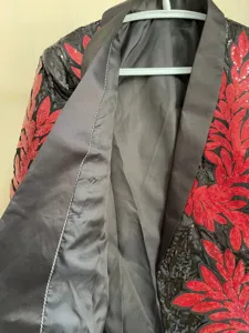Close-up detail of men's sequin blazer with red embroidered floral patterns and satin lapel.