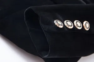 Close-up of velvet blazer sleeve cuff with decorative gold embossed buttons detail.