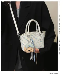 Detailed view of fashionable women crossbody bucket bag with cute cartoon print and bear charm.