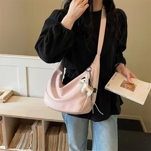 Detail view of pink slouchy crossbody dumpling bag with cute horse charm and stylish design.
