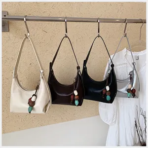 Minimalist underarm shoulder bag for women, chic hobo tote with beaded pendant, versatile daily bag.