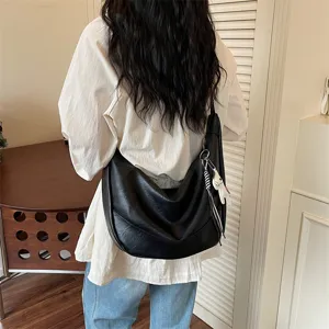 Stylish black leather shoulder hobo bag, trendy dumpling crossbody bag with cute animal charm details.