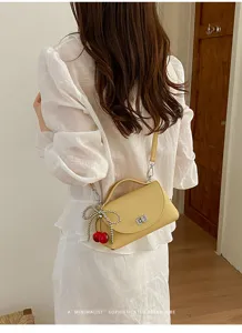 Chic yellow leather crossbody bag with cherry pendant, stylish retro mini shoulder bag.