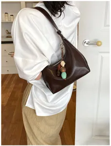Detailed view of brown leather underarm shoulder bag with chic colorful bead pendant accessory.
